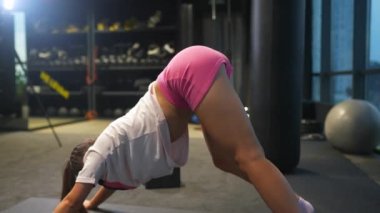 Aktif giyimli bir kadın spor salonunda egzersiz yapıyor.