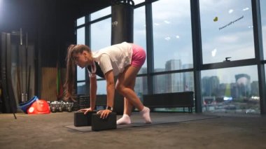 Aktif giyimli bir kadın spor salonunda egzersiz yapıyor.