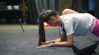 Aktif kıyafetli bir kadın spor salonunda esneme egzersizi yapıyor.