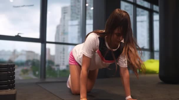 一个女人跪在体育馆里做运动来锻炼她的背部 — 图库视频影像