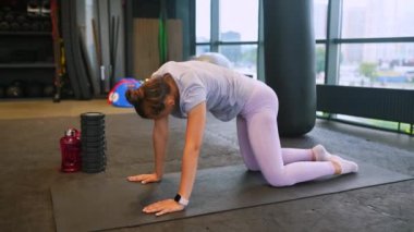 Bir kadın spor salonunda çalışmak için diz çöker..