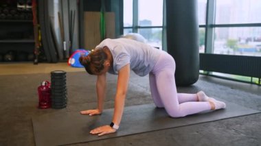 Bir kadın spor salonunda çalışmak için diz çöker..