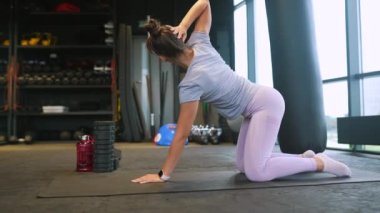 Bir kadın spor salonunda çalışmak için diz çöker..