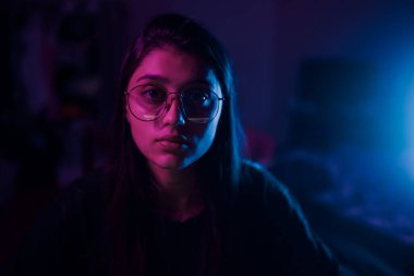 Young brunette woman working at the office at night with serious expression on face. Simple and natural looking at the camera.