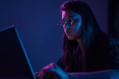 Attractive young woman working in home at night. Girl using laptop.