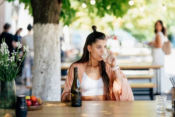 stock image Woman with a cold drink sitting in a cafe on the street