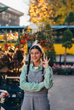Kot pantolon giyen çiftçi kadın gülümseyerek iyi bir işaret veriyor. Tarım kavramı.