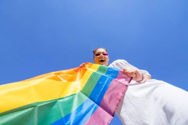 Genç bir kadın, LGBT toplumunu desteklemek için gökyüzüne gökkuşağı bayrağı dikiyor.