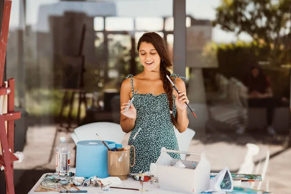 Young female artist with tools posing for camera