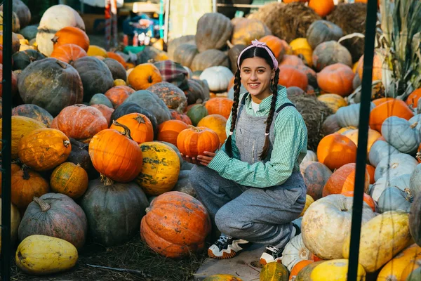 デニムジャンプスーツの幸せな農家の女性は熟したカボチャ 秋の収穫を選択します 農業の概念 — ストック写真