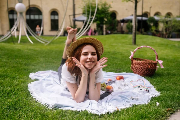 快乐的年轻女子躺在公园草坪上的毛毯上 — 图库照片