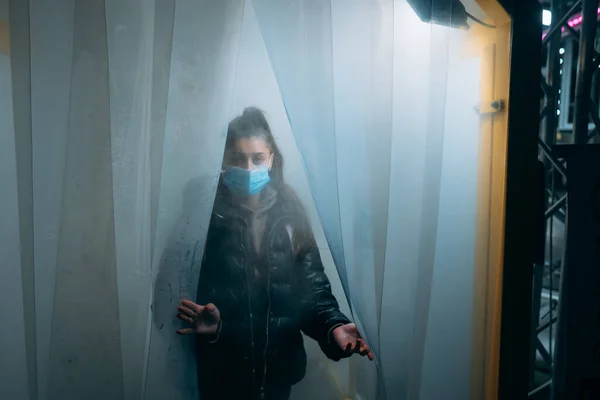 Young beautiful woman in a medic mask is staying in a disinfection tunnel