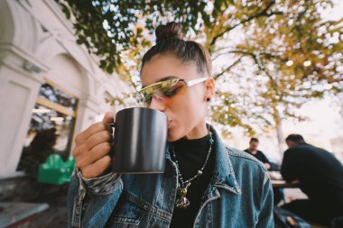 Modern sokak kafesinde çay içerken güzel, genç bir bayan.