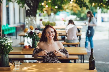 Arka plandaki yazlık kafede terasta kahve içen iki kız arkadaşın yakın plan portresi.