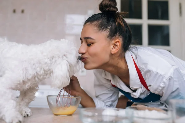 Young Woman Kitchen Kisses Cute White Maltese Dog Sniffing Meal — Stock Photo, Image