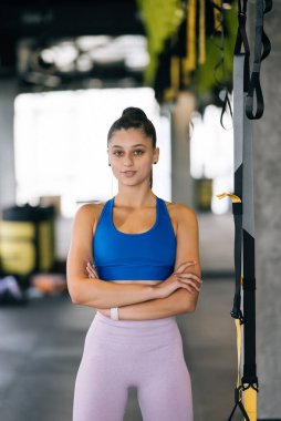 Spor salonunda kameraya poz veren güzel bir genç kadın. Şehvetli genç kadın, kameraya bak.