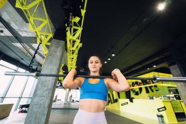 Güzel ve güçlü genç bir kadın kalçalarının büyümesi için halterle mekik çekiyor..