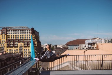 Kadın evin çatısında sicim yapıyor.