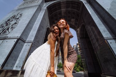 İki güzel gülümseyen yeniyetme kadının son moda yaz kıyafetleri içinde portresi. Sokakta poz veren kaygısız kadınlar..