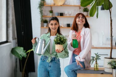 Elinde su kovası ve saksıda saksı olan genç kadınlar.