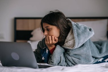 Yatakta yatarken dizüstü bilgisayarda çalışan kadın