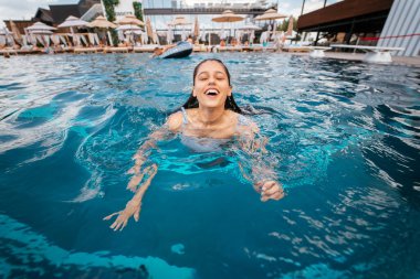 Mavi havuz suyunda genç bir kadın yüzücü. Yakın görünüm