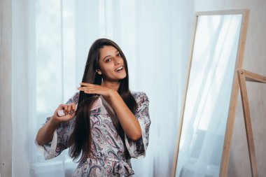 Aynanın önünde saçını tarayan bir kadın..