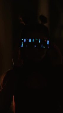 LED gözlüklü, neon ışığı altında duran ciddi bir siber kadın.