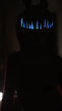 LED gözlüklü, neon ışığı altında duran ciddi bir siber kadın.