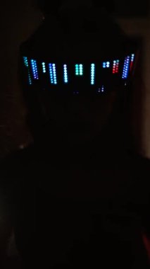 LED gözlüklü, neon ışığı altında duran ciddi bir siber kadın.