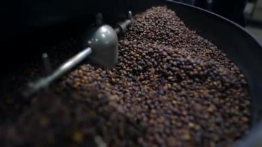 Otomatik makinede kızartıp kaynaşan Arabika kahve çekirdekleri. Yakın çekim ve seçici odaklanma.