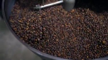 Otomatik makinede kızartıp kaynaşan Arabika kahve çekirdekleri. Yakın çekim ve seçici odaklanma.