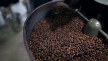 Otomatik makinede kızartıp kaynaşan Arabika kahve çekirdekleri. Yakın çekim ve seçici odaklanma.