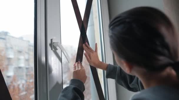 Woman Tapes Windows Criss Cross Room Minimize Bomb Damage Avoid — Stock Video