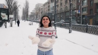 Yünlü kazaklı mutlu kız kış anlarının tadını çıkarıyor. Dışarıda gülen kadın karlı bir sabahta eğleniyor.