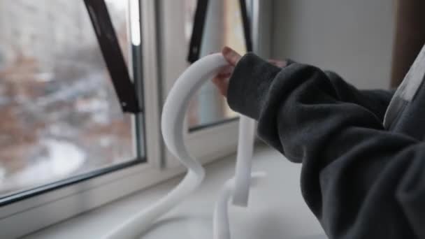 窓を密閉するためのフォームテープを測定する女性の手のクローズアップ屋内 — ストック動画