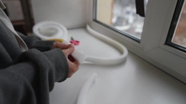 窓を密閉するためのフォームテープを測定する女性の手のクローズアップ屋内 — ストック動画