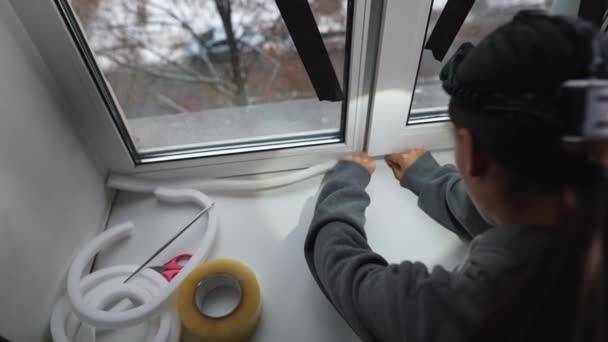女性は窓の屋内に封止ゴムテープを接着する — ストック動画