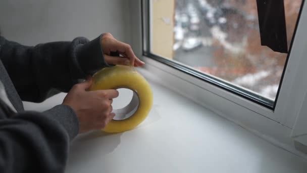 Молода Жінка Запечатує Вікно Стрічкою Приміщенні — стокове відео