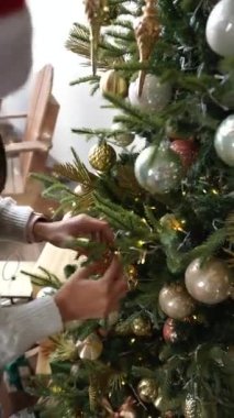 Genç bir kadın Noel balosunu Noel ağacında süslüyor.