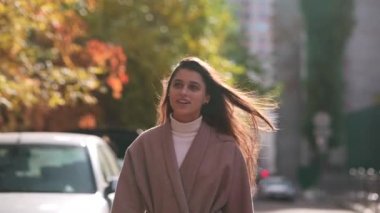 Paltolu güzel bir kadın sonbahar şehrinin caddesinde yürüyor.