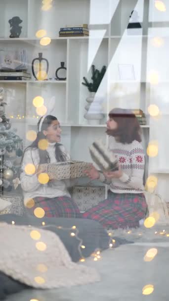 Patrząc Przez Okno Dwie Dziewczyny Wymieniają Prezenty Świąteczne Siedząc Obok — Wideo stockowe