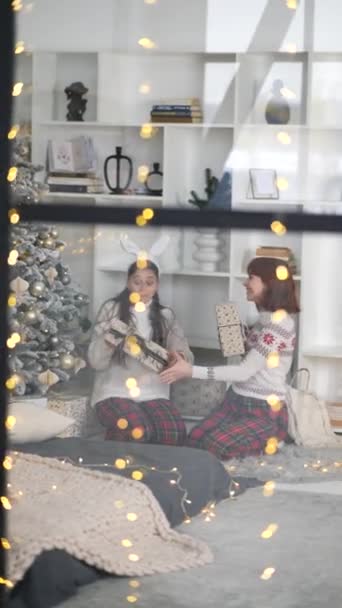 Looking Window Two Girlfriends Exchanging Christmas Presents Sitting Christmas Tree — Stock Video