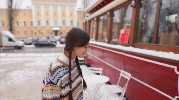 Молодая Счастливая Женщина Входит Кафе Снежной Улицы — стоковое видео