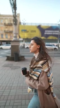 Mutlu gülümseyen genç bir kadın şehirde video görüşmesi yapıyor. İnternet günlüğü için selfie ya da video çeken şık bayan gezgin.