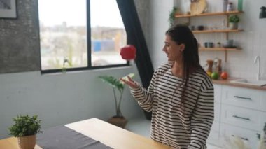 Mutfakta yemek pişirirken mutfakta eğlenen neşeli genç bir kadın.