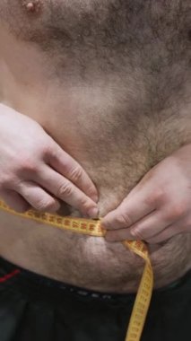 Sporcu adam spor salonunda belini bir santimetre bantla ölçüyor. Yüksek kaliteli FullHD görüntüler