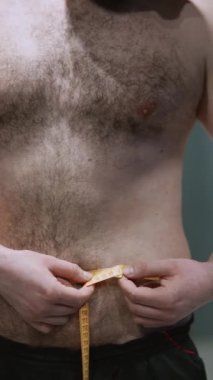 Sporcu adam spor salonunda belini bir santimetre bantla ölçüyor. Yüksek kaliteli FullHD görüntüler