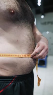 Sporcu adam salonda göğsünü bir santimetre bantla ölçüyor. Yüksek kaliteli FullHD görüntüler