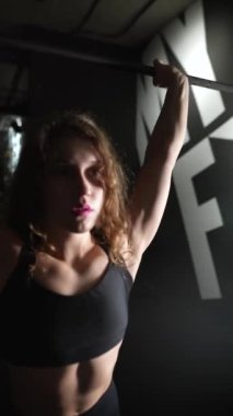 Atletik Güzel Kadın, vücut geliştirme spor salonu rutininin bir parçası olarak halteri kaldırıyor. Portreyi kapat